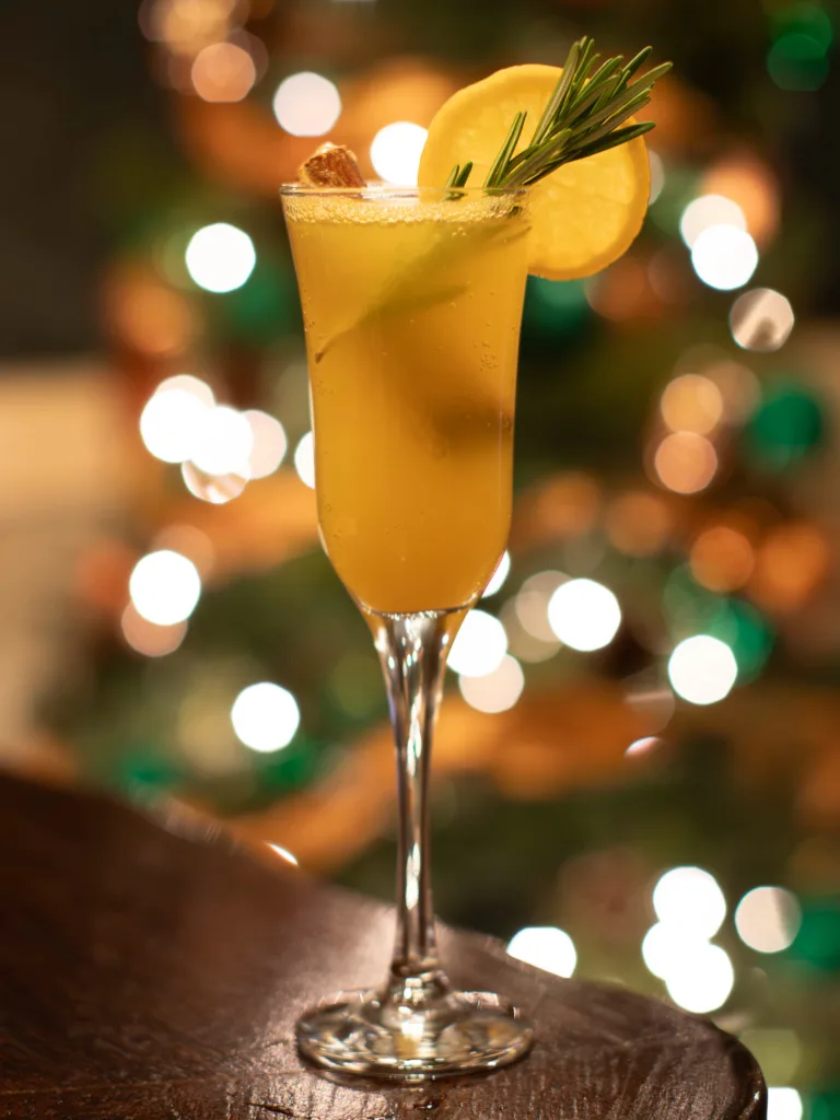 The Orange and Rosemary Fizz Mocktail is a delightful blend of freshly squeezed orange juice and sparkling lemonade, creating a zesty and effervescent base.