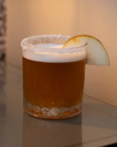 Pear Crumble Whiskey Sour Cocktail - A dessert-inspired whiskey sour built on pear and apple: warm blended whiskey, marzipan-sweet amaretto, ripe pear and orchard apple, cinnamon-spiced foam, finishing rich, cosy and crumble-like.